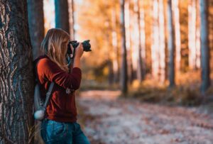 A woman taking a picture in the woods